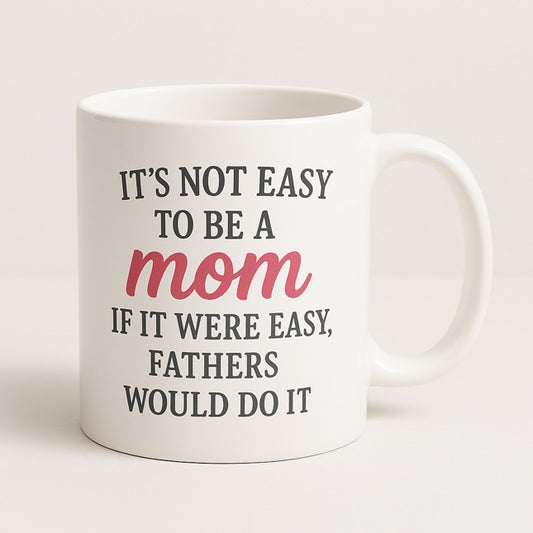 Λευκή κεραμική κούπα με τη φράση "It’s not easy to be a mom – If it were easy, fathers would do it" σε μαύρο και ροζ, ιδανική για μαμάδες - The Gift Box thegiftbox.gr